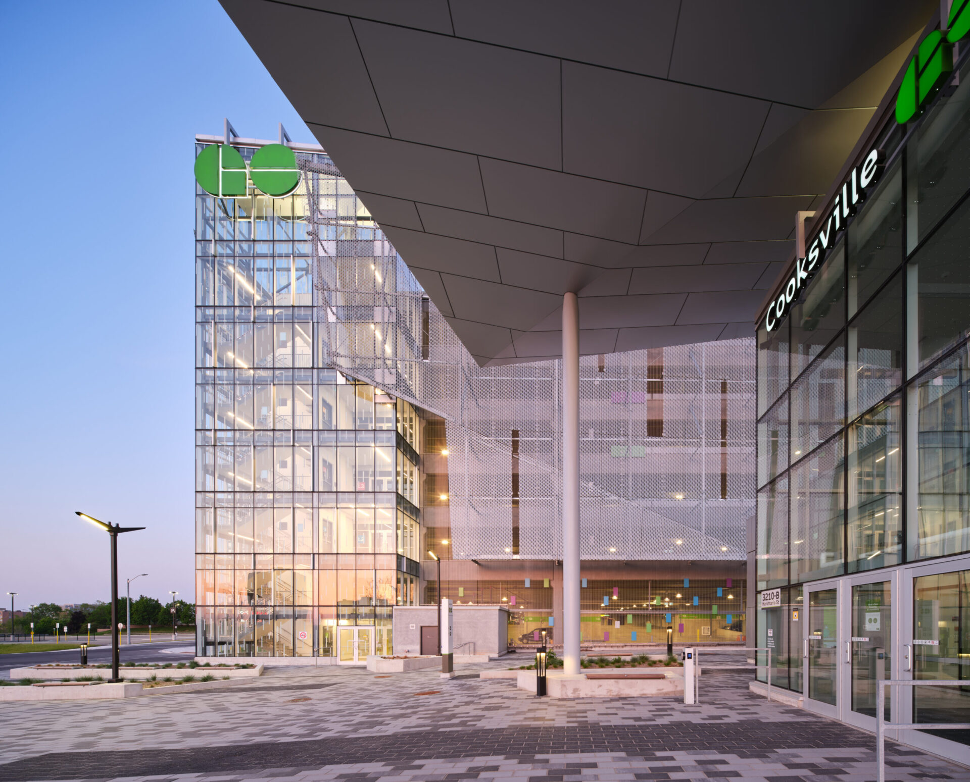 A sprawling glass building showcasing impressive architecture and engineering, distinguished by a vibrant green sign.