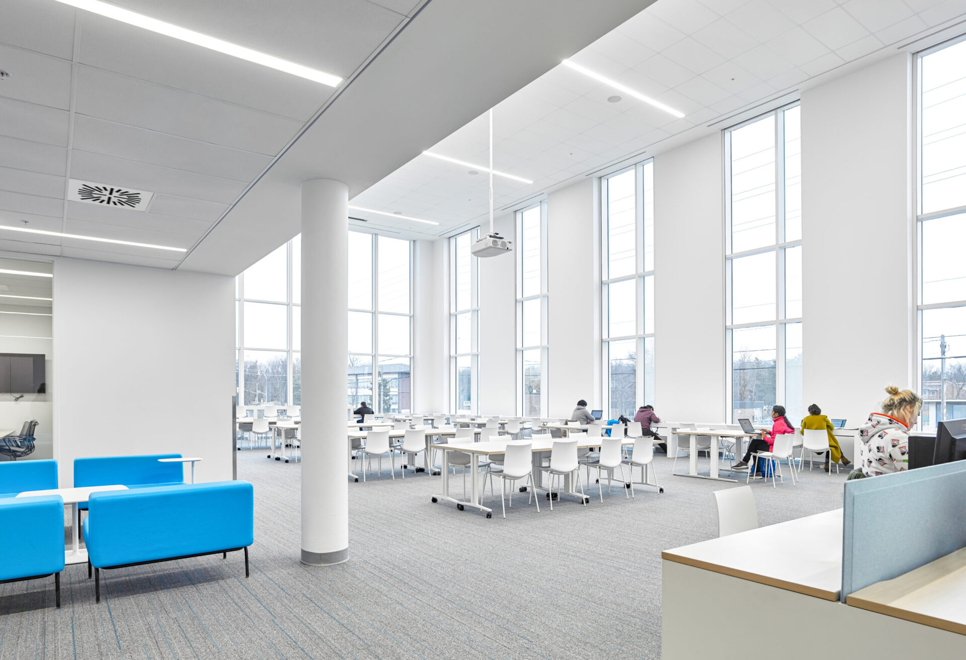 A spacious open space with blue tables and chairs inside a building.