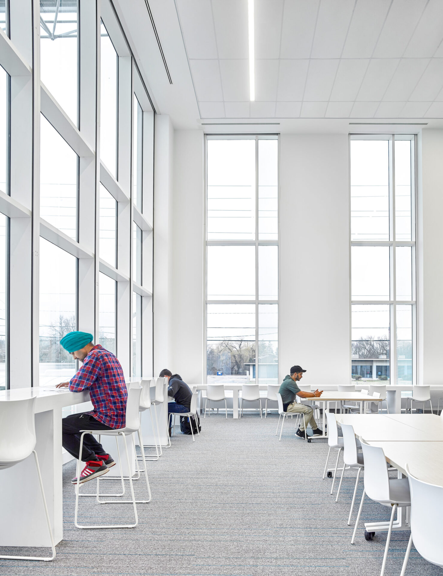 A group of people studying at tables in an architecturally designed library building.