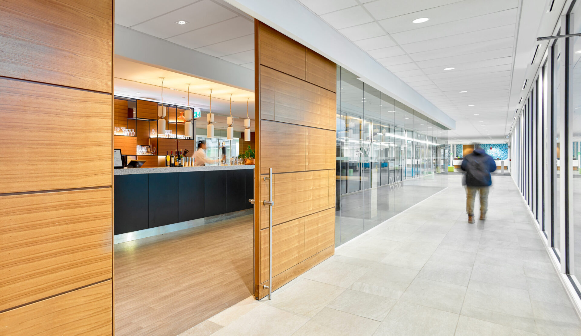 A person walking down a hallway in an office building showcasing its architecture.