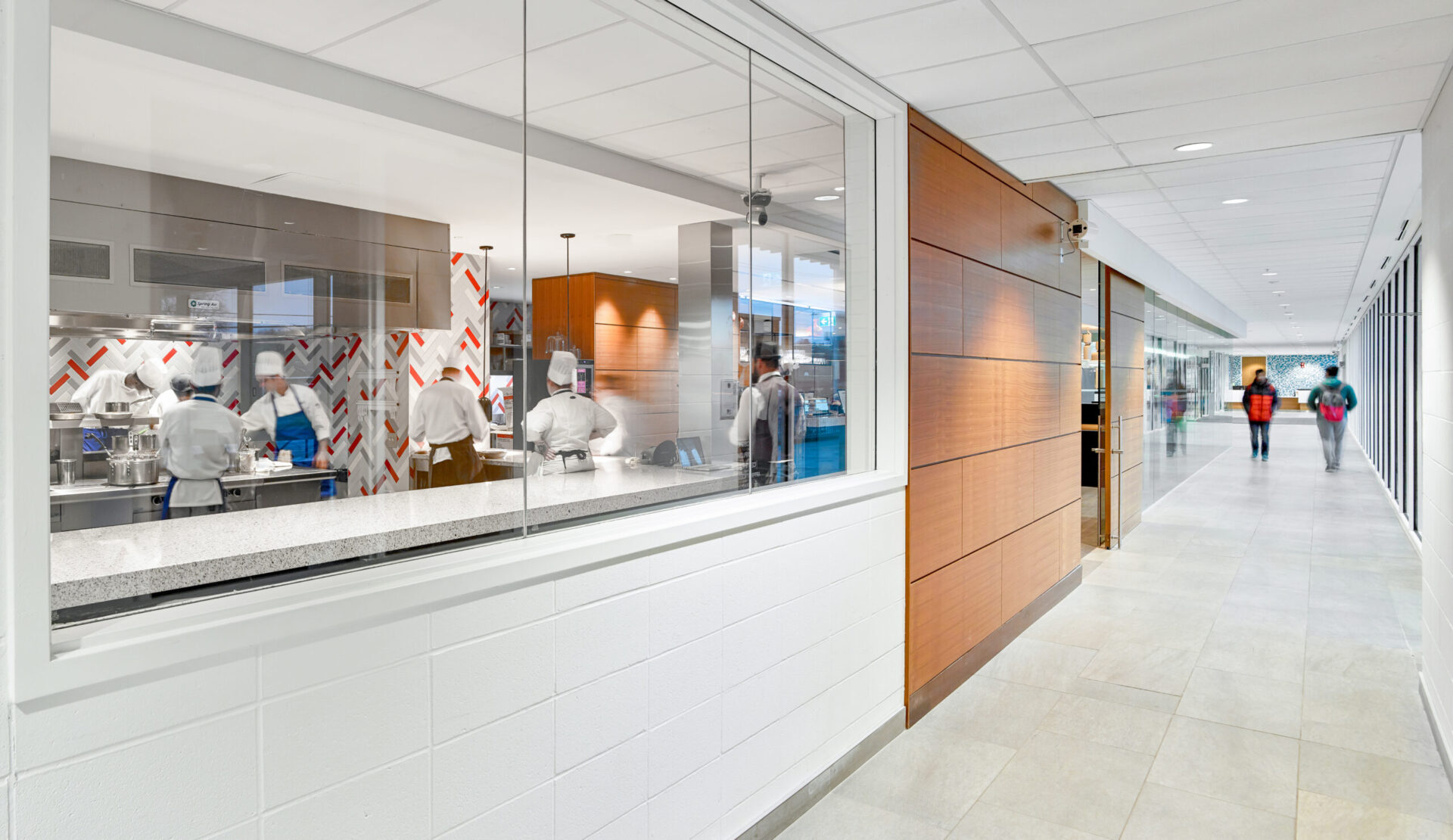 An architectural hallway with people walking down it.