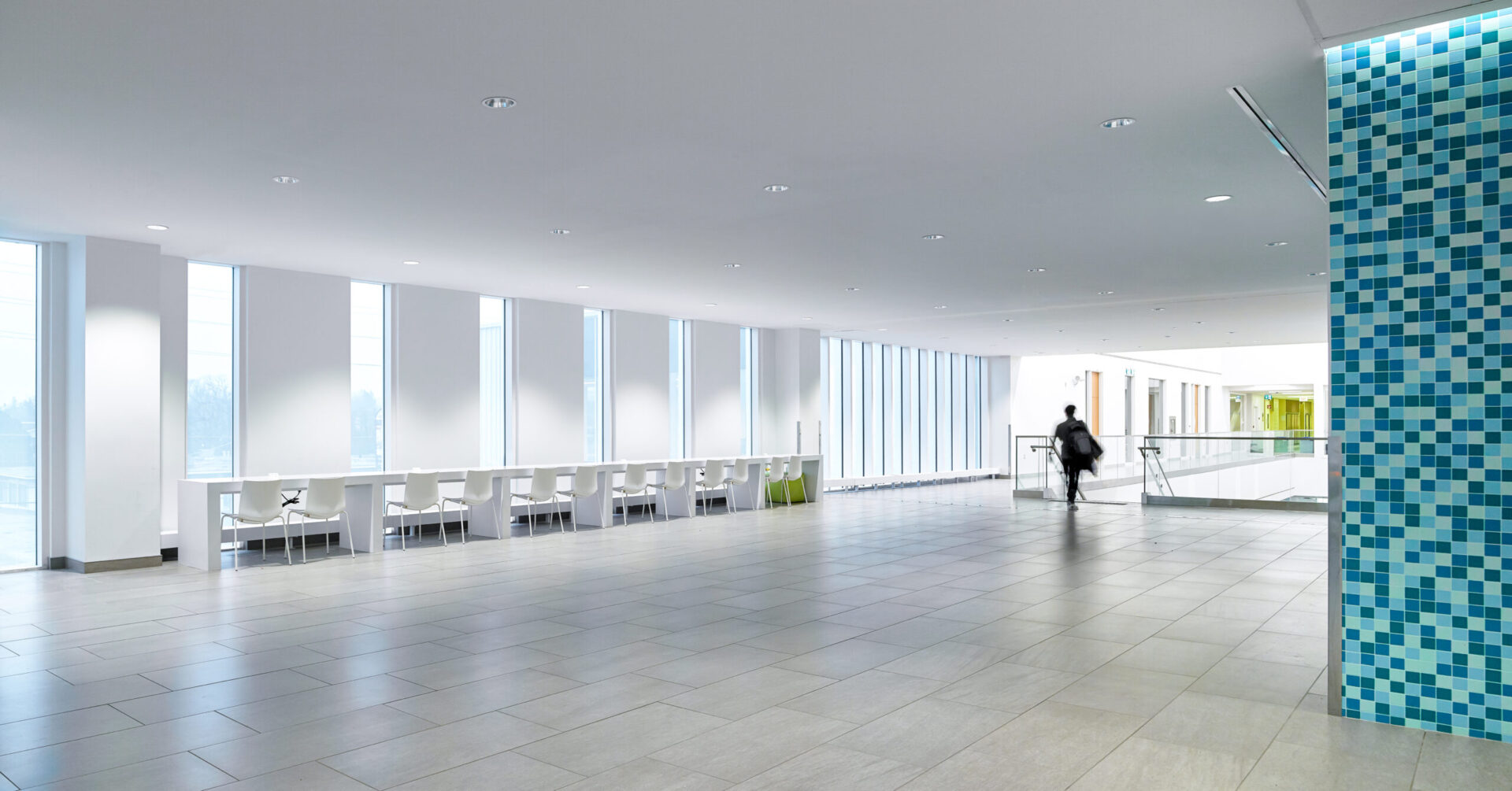 A person walks through a blue tiled building lobby.