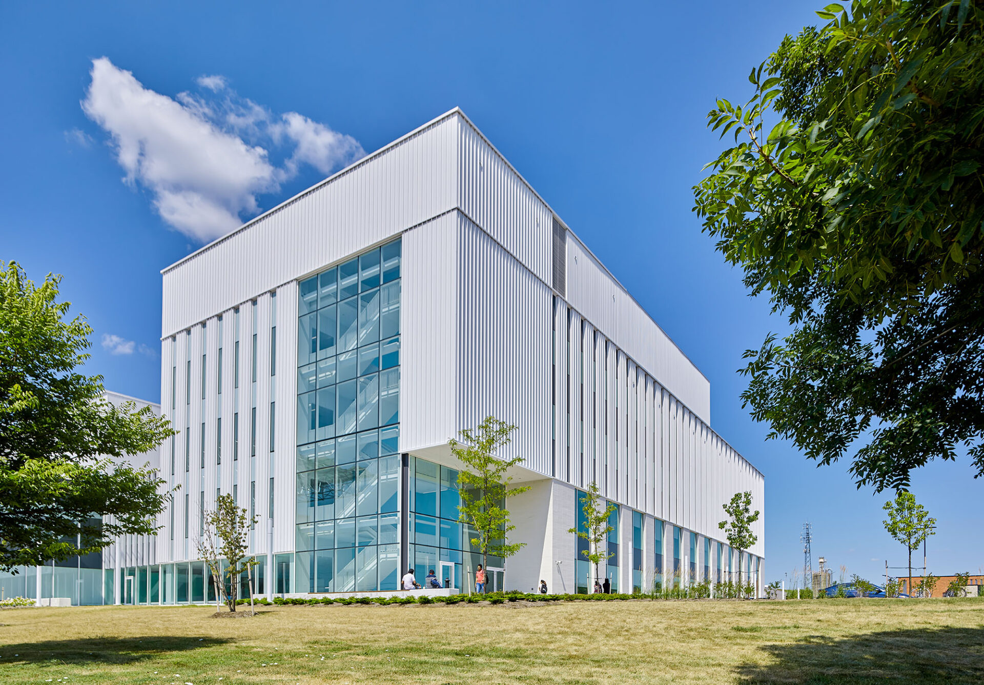 A white engineering building in a grassy area with trees.