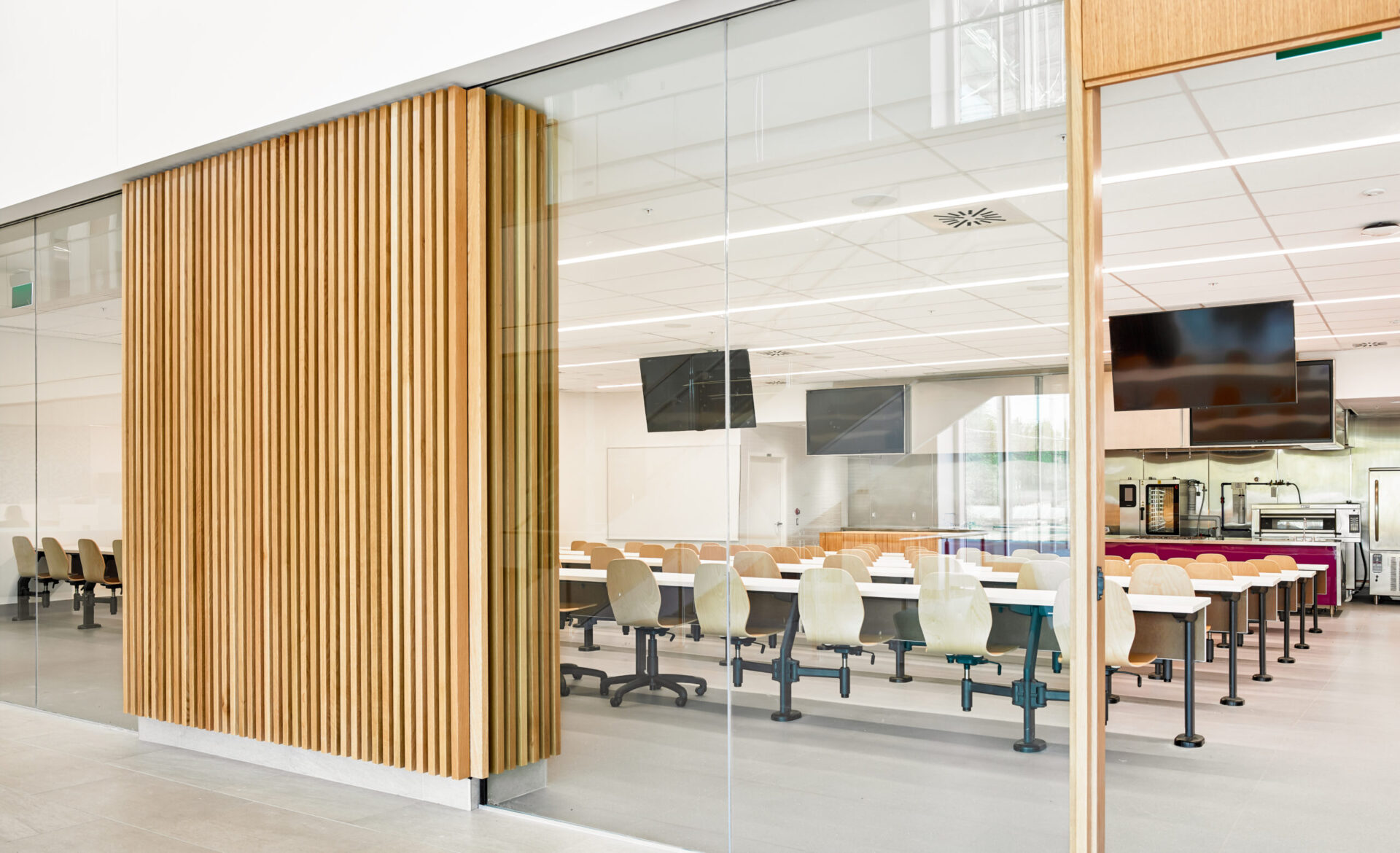 An architectural glass wall enhances the design of a room with tables and chairs.