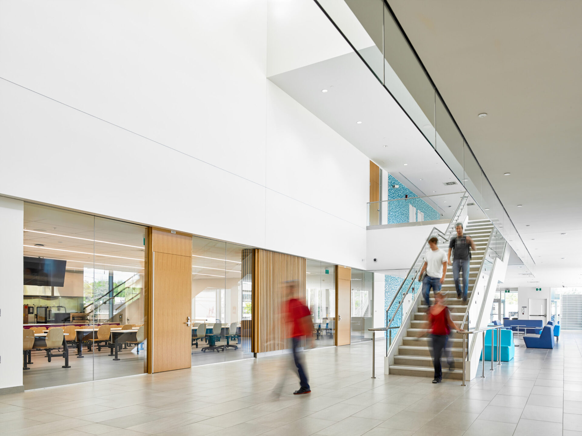 The lobby of an architecturally designed building with people walking down the stairs.