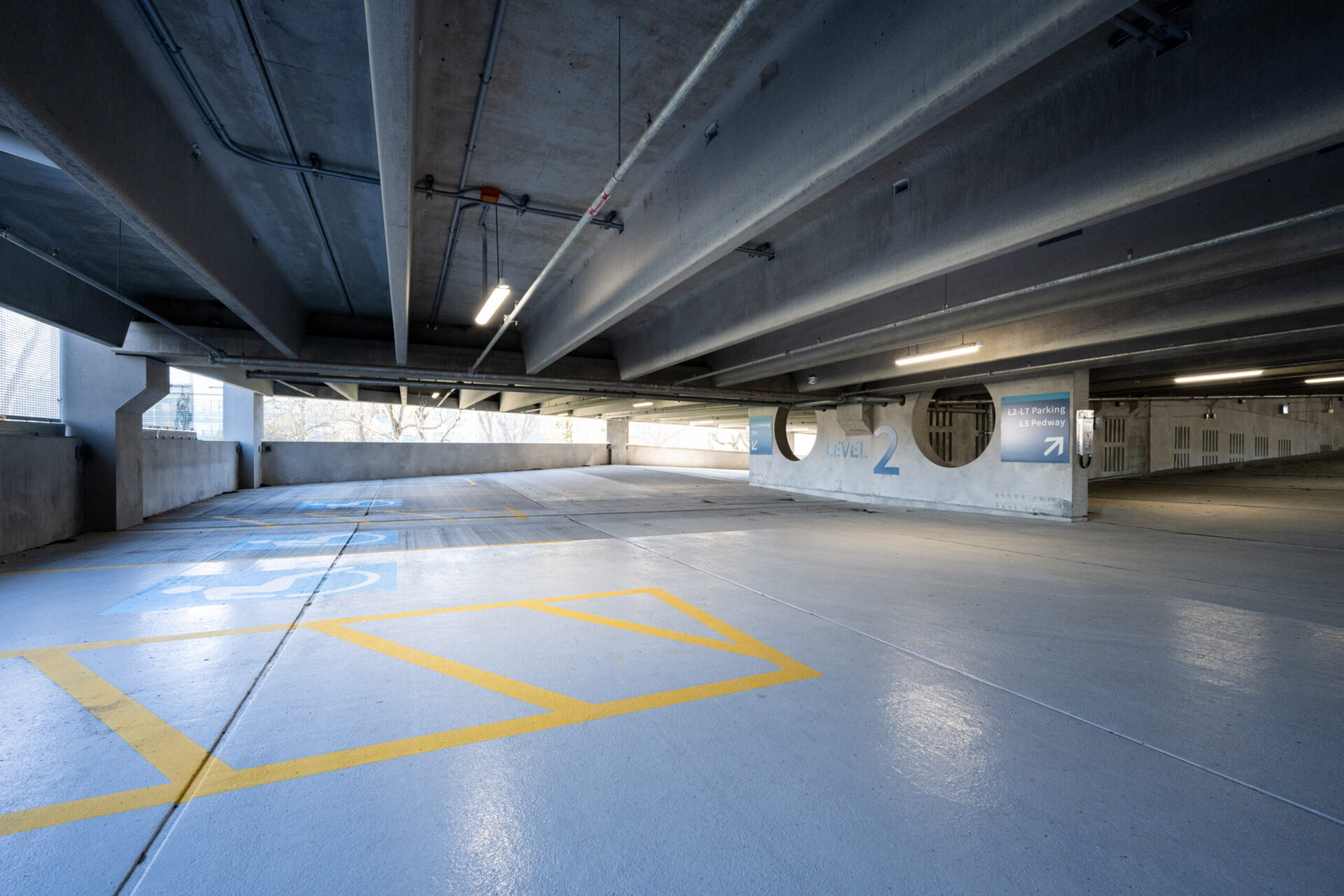 An empty parking garage with yellow lines on the floor showcases architectural design.