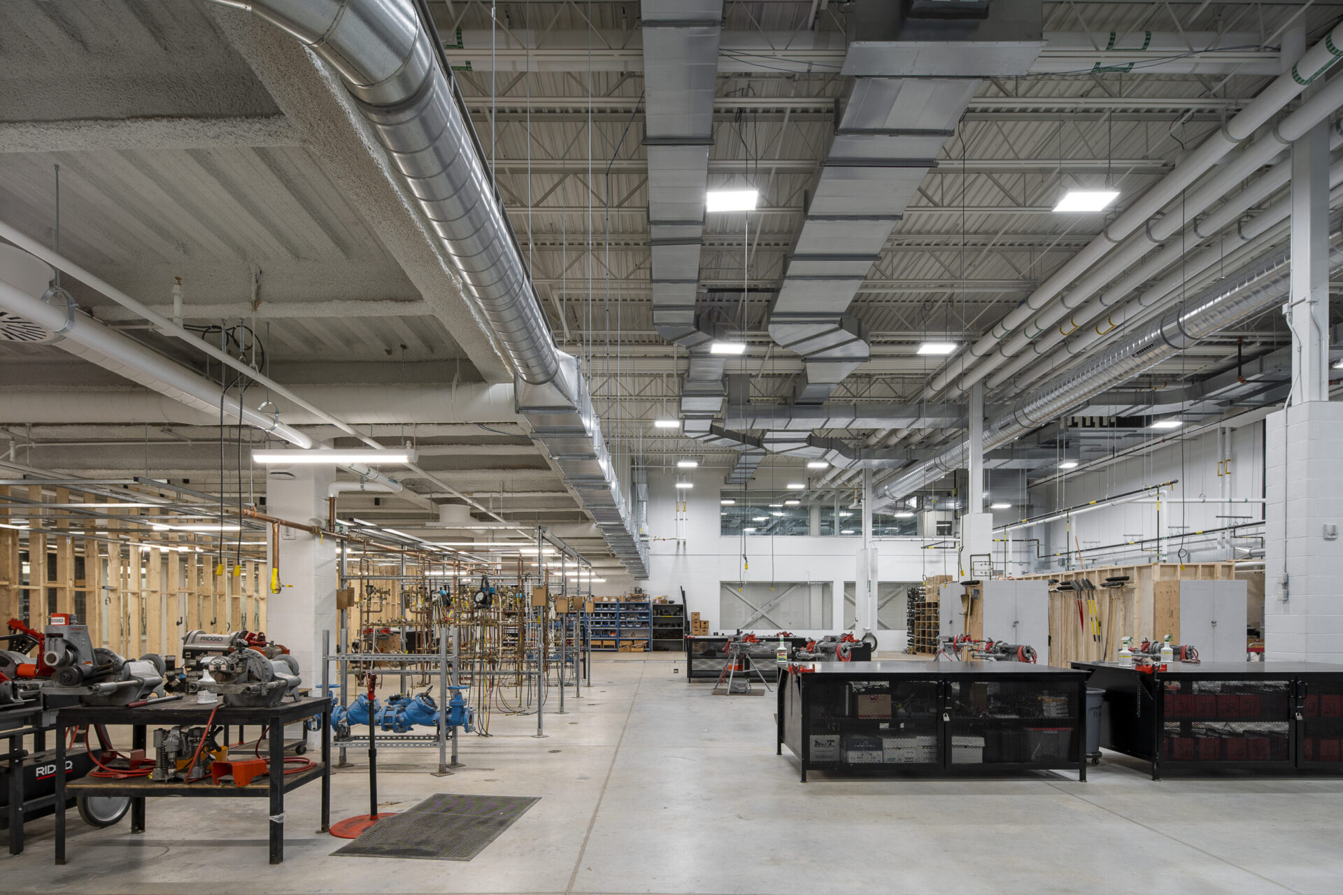 The inside of a factory building with many machines and pipes.
