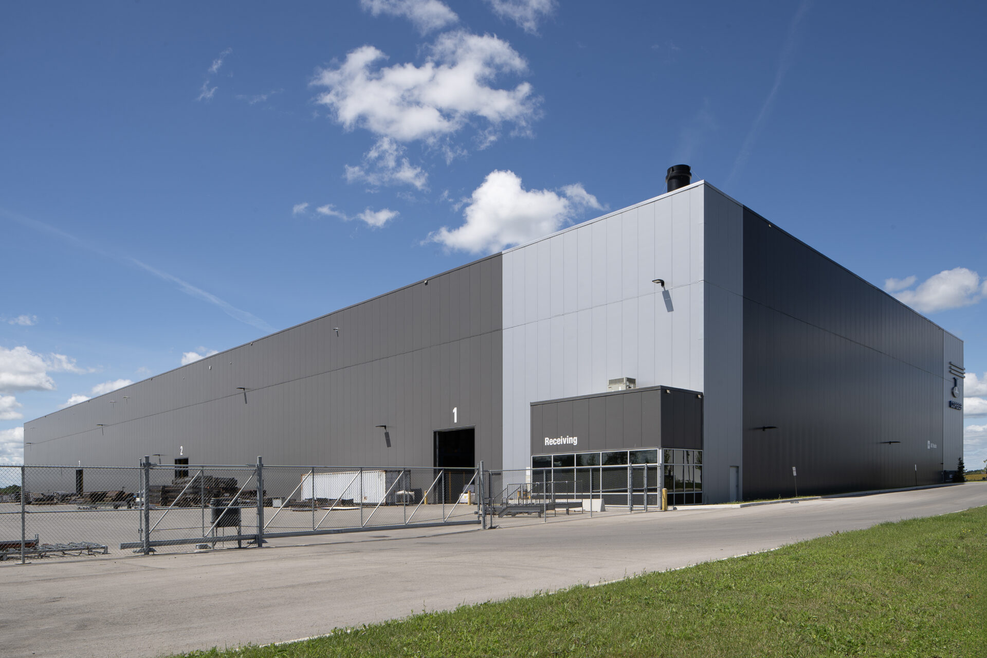 A large steel galvanizing plant with a fence in front.