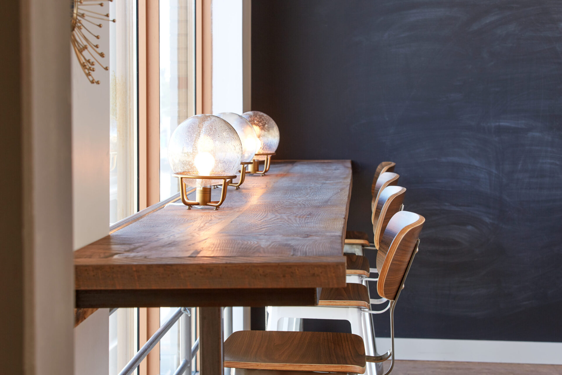 An architecturally designed wooden bar with stools in front of a window.