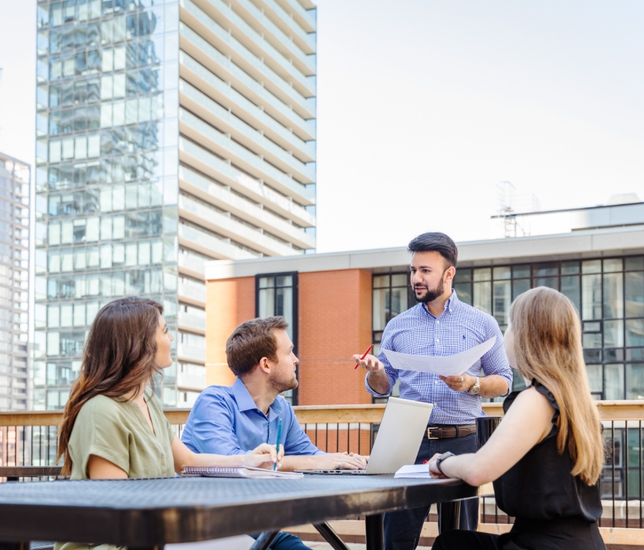 A group of people sitting around a table with laptops collaborating on engineering projects.