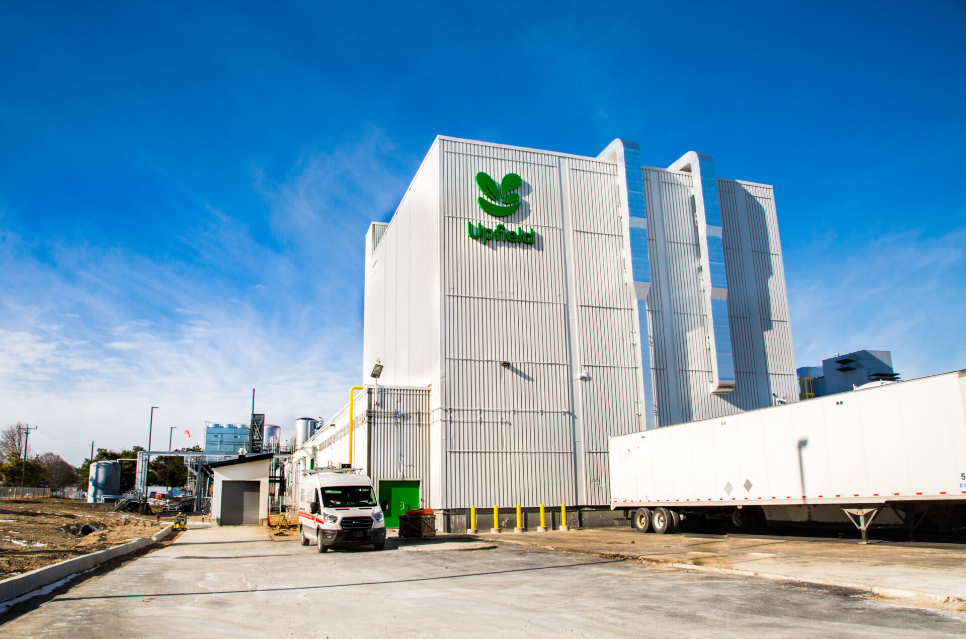 A green building with a truck parked in front of it.