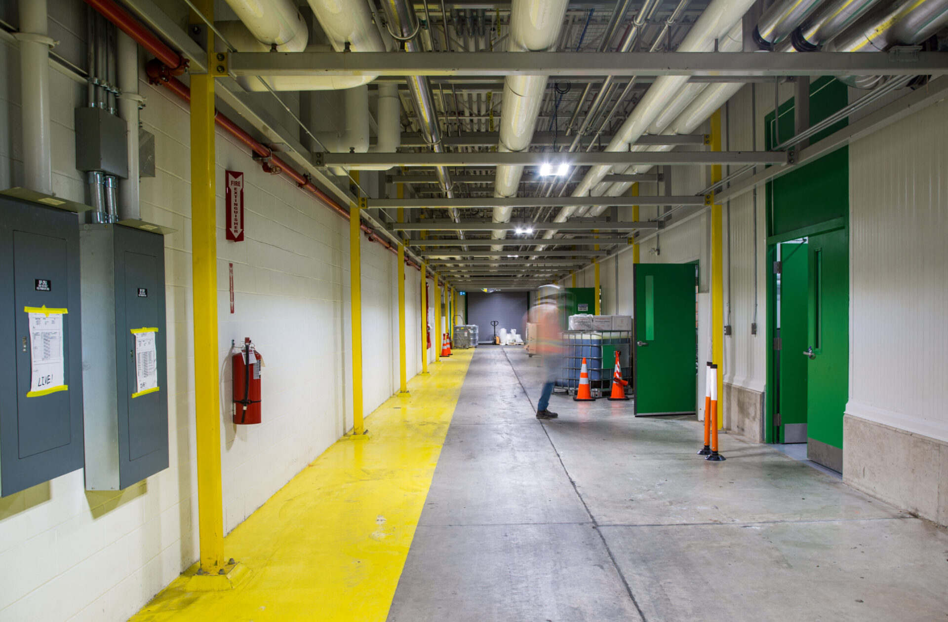 A warehouse hallway illuminated by yellow and green lights, showcasing engineering and architecture.