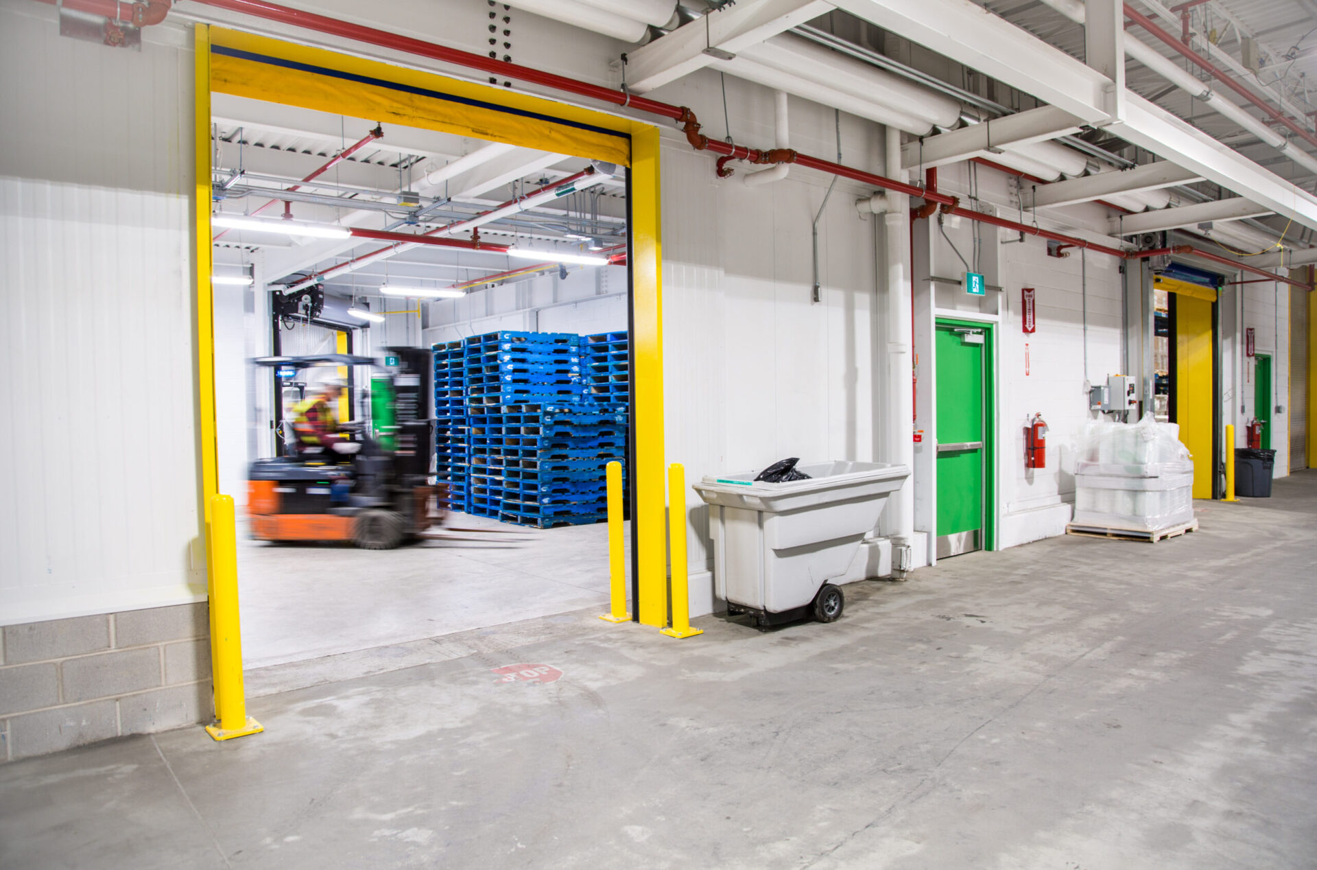 A forklift in a warehouse with yellow doors demonstrating engineering.