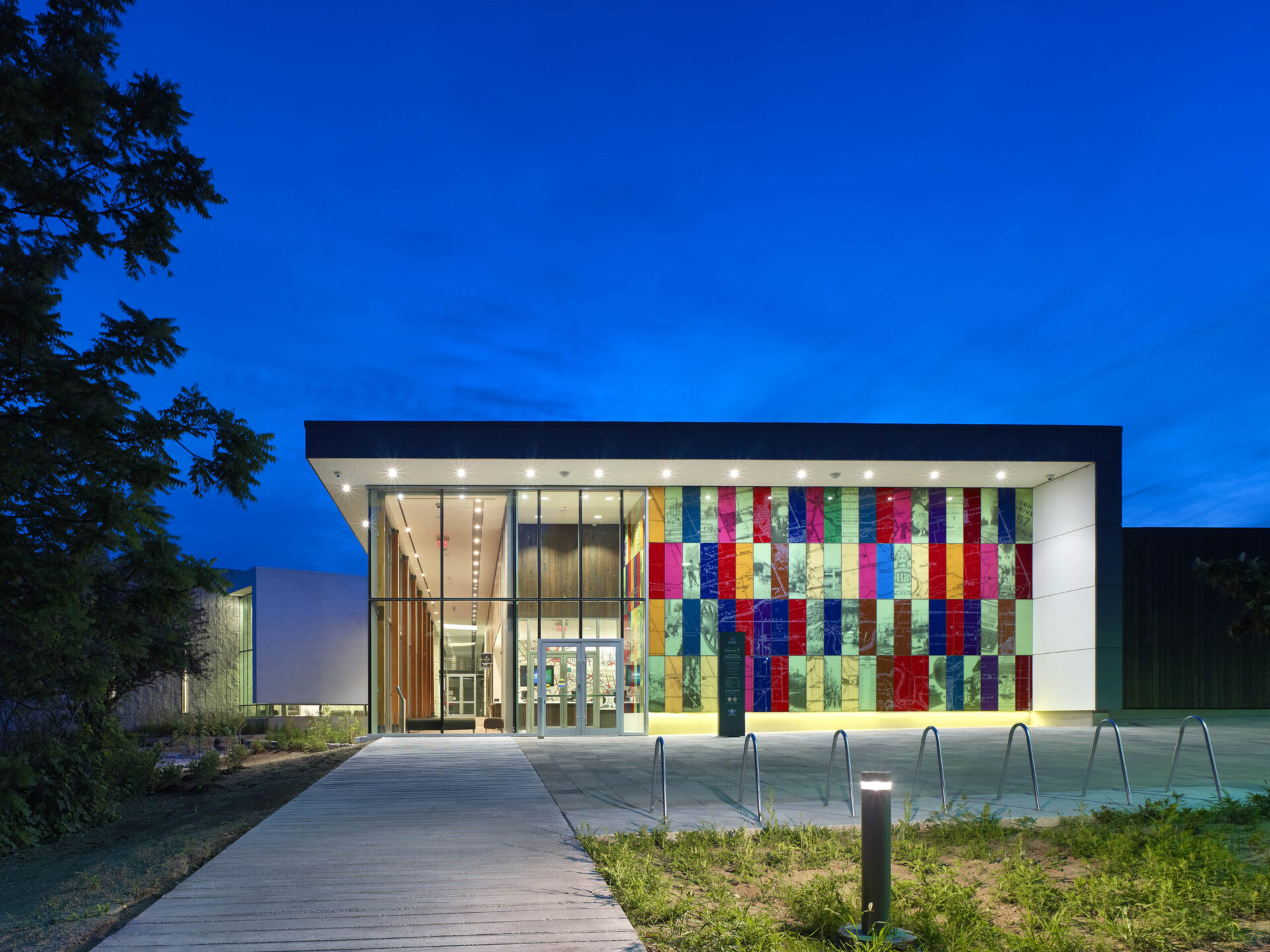 A building displaying the art of engineering with a colorful glass facade at night.