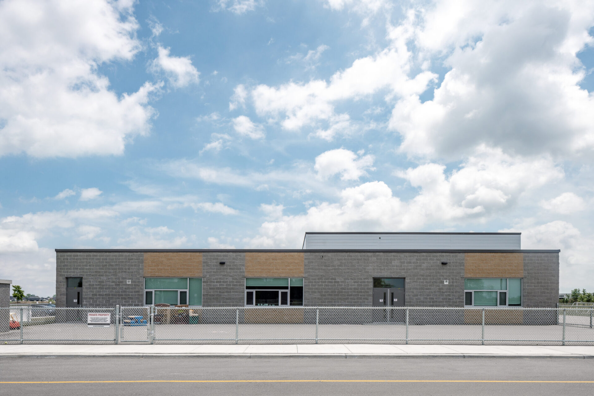 A well-engineered building with a fence and a cloudy sky.