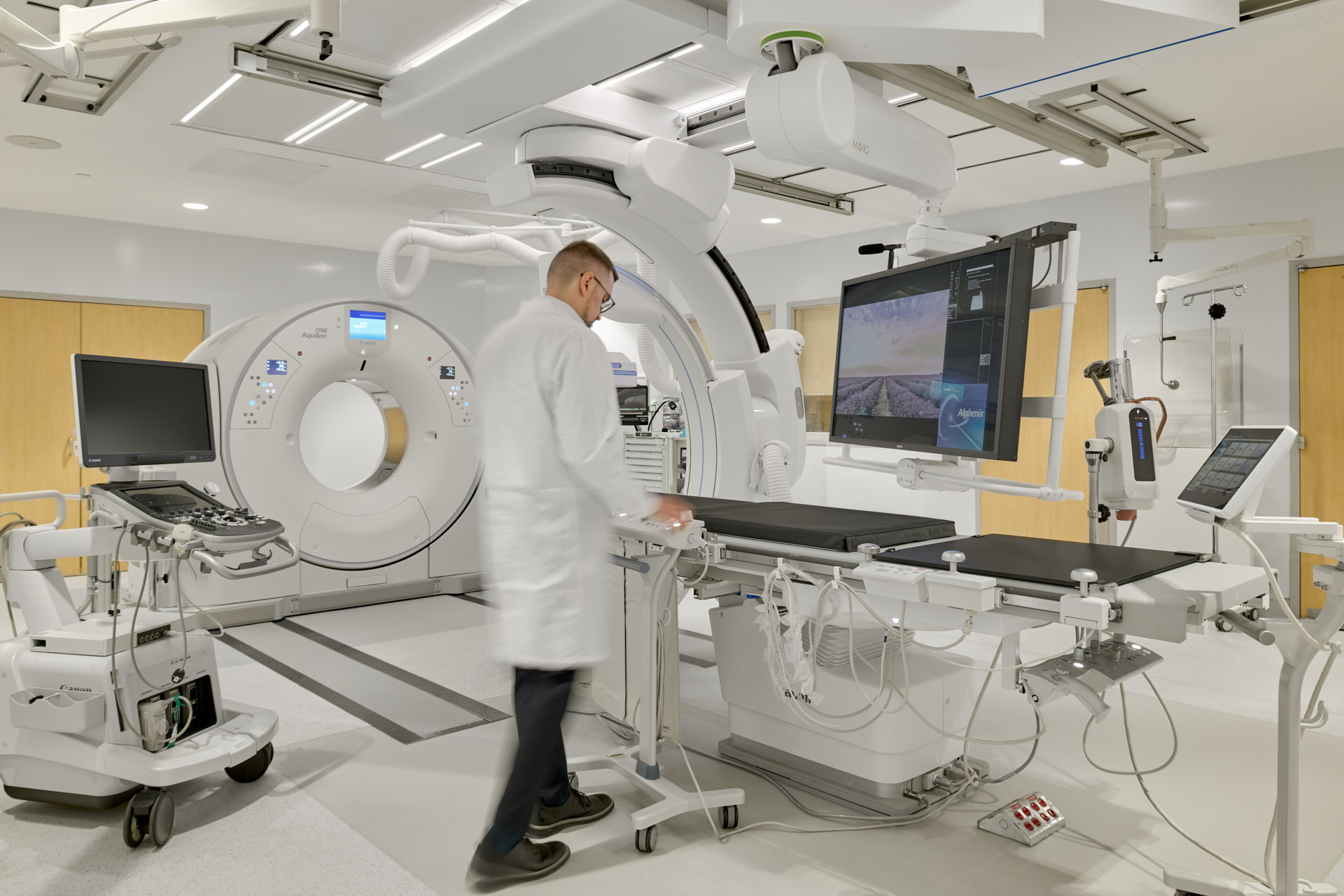 Technician standing in front of IR scanning device screen, showing a few windows pop ups.. Right side of room looking left.