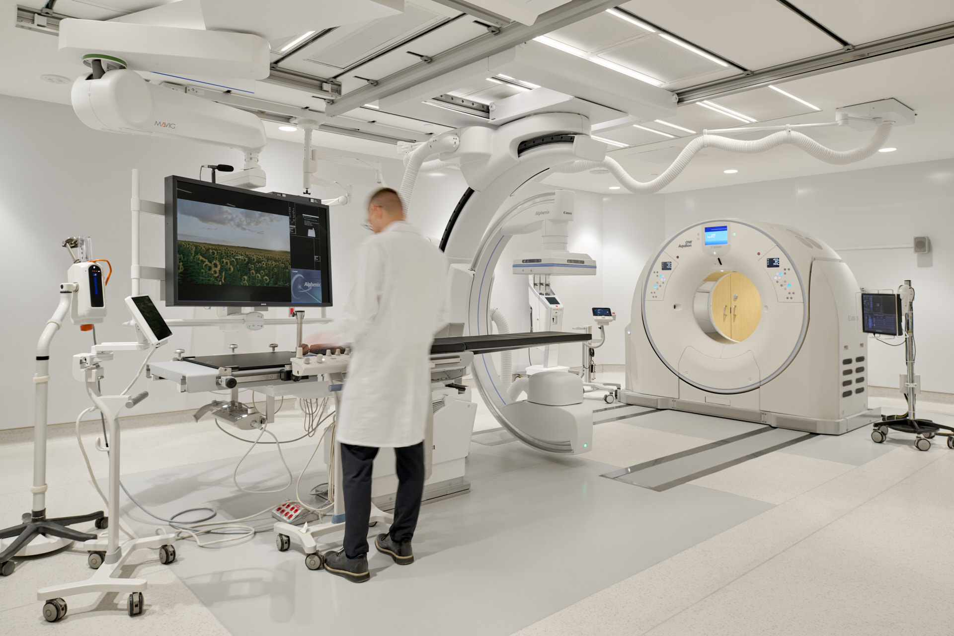 Technician standing in front of IR scanning device screen, showing a few windows pop ups.. Left side of room looking right.